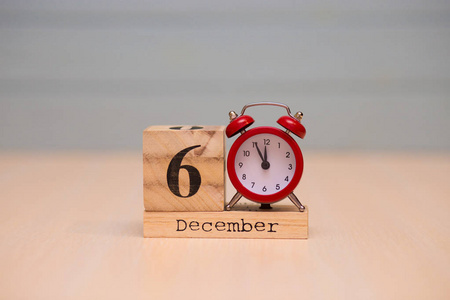 十二月六日设置在木制日历和红色闹钟与蓝色背景。 钟显示午夜五分钟