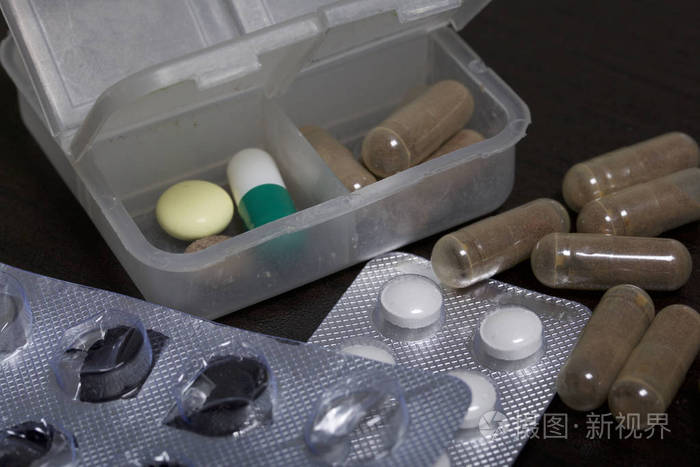 桌子上的药片和水泡一些开始了附近有几片药丸在黑暗的背景上