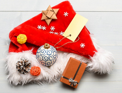 寒假的属性。新年和圣诞装饰品。圣诞老人帽子白色背景顶视图。圣诞老人帽子与圣诞礼品盒。圣诞老人送的圣诞礼物注意细节