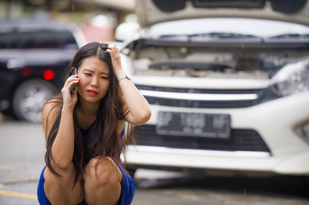 年轻的绝望和沮丧的亚洲韩国妇女在压力下被困在街头，遭受汽车发动机故障，机械故障，打电话寻求帮助，保险援助服务
