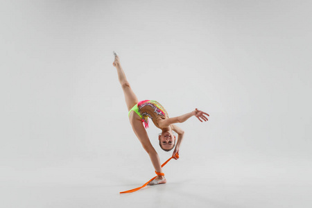这个十几岁的小女孩在灰色的工作室背景下用跳绳做体操。体操伸展健身生活方式训练运动概念