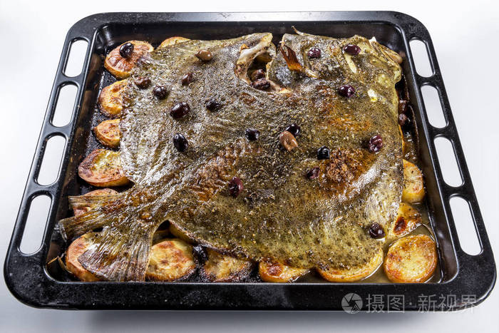烤盘烤鱼中的煮熟的整块龟头鱼,在白色背景下分离出土豆橄榄和芳香