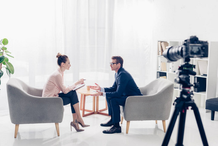 采访视频人名条一位英俊的商人在接受记者的采访时,他们坐在扶手椅上