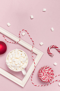白色杯子与棉花糖糖果罐头礼品盒红色球包装花边相框在粉红色背景顶部视图平面铺设。冬季传统饮料食品节日装饰庆祝圣诞新年