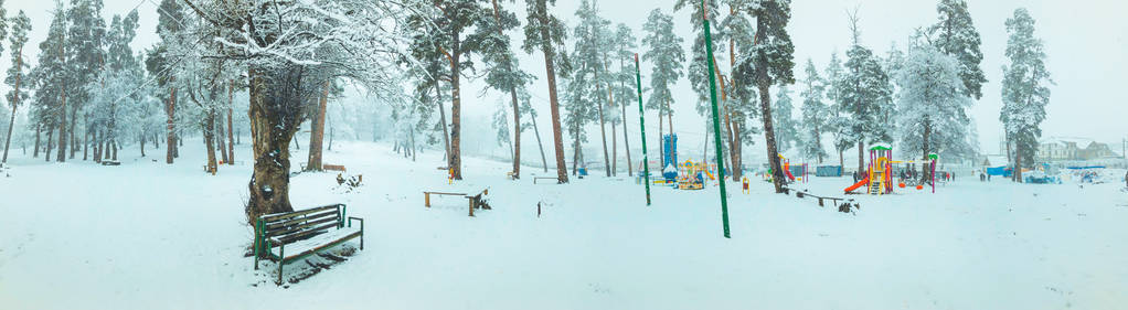 降雪。雪中的树。孩子们在雪地里散步。在雪中的树下板凳。巴库里亚尼山区滑雪胜地