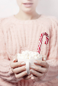 圣诞新年饮料，白色杯子与棉花糖在女性手中针织粉红色毛衣和糖果罐。冬季传统食品节日庆祝节日