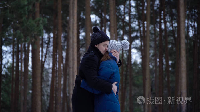 冬天, 年轻夫妇在公园里拥抱和亲吻.幸福的一对在一起.年轻人在冬天森