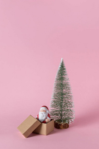 小圣诞老人，粉红色背景上有礼品盒。 最低限度的圣诞节或新年概念。