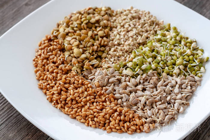 一组不同发芽的种子,用于在白色盘子上健康饮食.