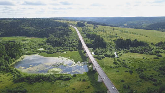 森林中农村道路交通的最高景观。剪辑。公路穿过森林沼泽与多云的天空