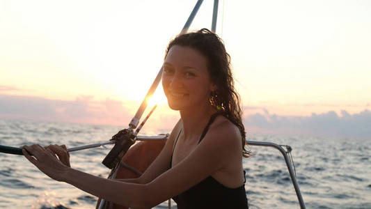 在游艇上穿着泳衣在日落时欣赏海景的快乐女人的肖像