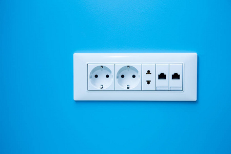 浅蓝色墙壁上的插座，一个具有互联网连接的多个插座，两个欧洲型和一个美国型插座。