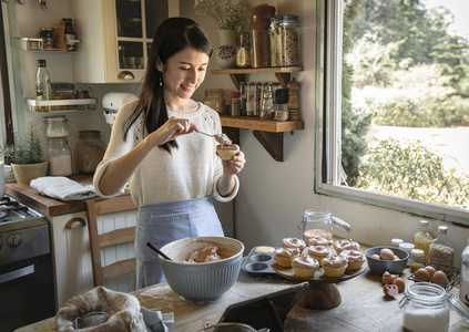 女人加巧克力糖霜到纸杯蛋糕食品摄影食谱想法