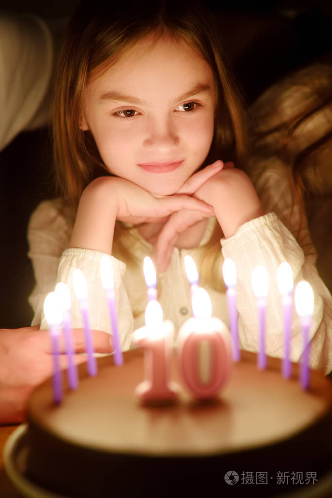 可爱的十岁女孩许愿,然后在她的生日蛋糕上吹蜡烛. 孩子庆祝她的生日.