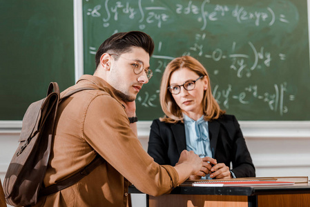 女教师在教室里用黑板看年轻学生的背景