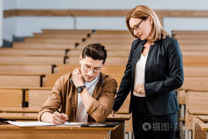 女大学教师在课堂上看男学生写作考试