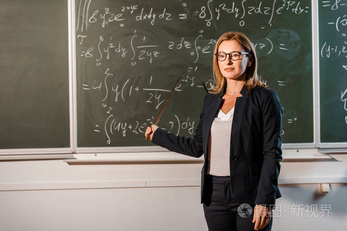 漂亮的女教师,用木指针在教室里讲解数学方程式