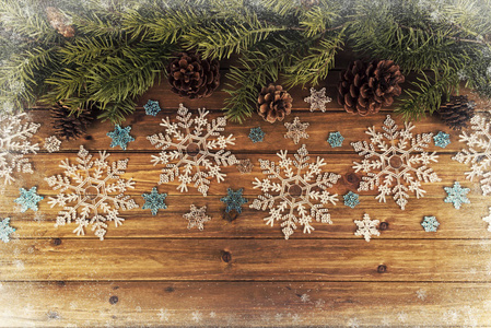 圣诞树的树枝和雪花装饰在自然木桌的背景上。 直接在上面。