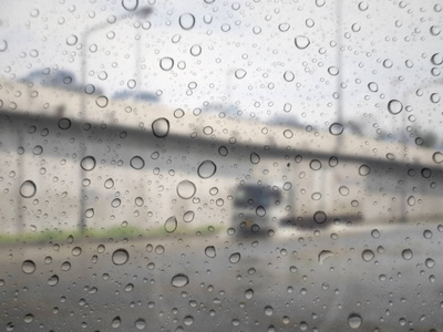 关闭玻璃背景上的雨滴。 路上交通不合重点