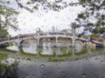 关闭玻璃背景上的雨滴。 桥梁偏离焦点