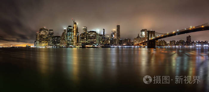 在雾蒙蒙的夜晚，曼哈顿市中心和布鲁克林大桥的全景。 在纽约，纽约，美国。