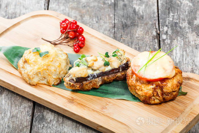 牛肉牛排和鸡胸肉配上西红柿和奶酪放在木制背景的切割板上热肉菜顶部