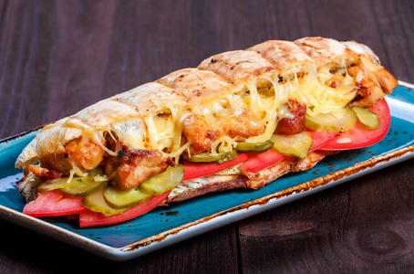 三明治从新鲜皮塔面包与鱼片烤鸡生菜片新鲜番茄泡菜和奶酪在黑暗的木制背景。 什什利克或什什烤肉串。 健康午餐