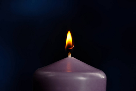 在黑暗的背景上燃烧着紫色的蜡烛