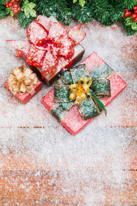 圣诞节和新年的概念与边界设计和复制空间在底部左装饰松糠冬青浆果和美丽的礼品盒在中间设置在木板与雪花。