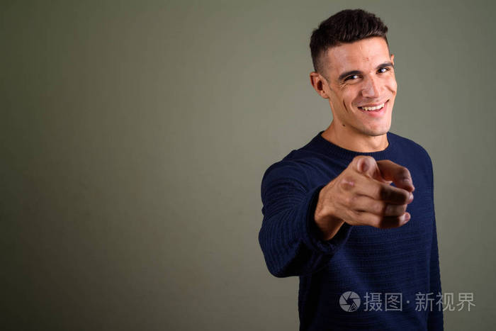 年轻英俊的男人用手指指着相机在彩色背景