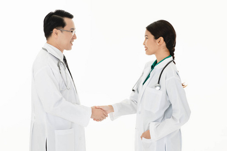 两名亚洲医生肩上穿着统一的听诊器，做握手，保健服务，团队合作，孤立在白色背景下。