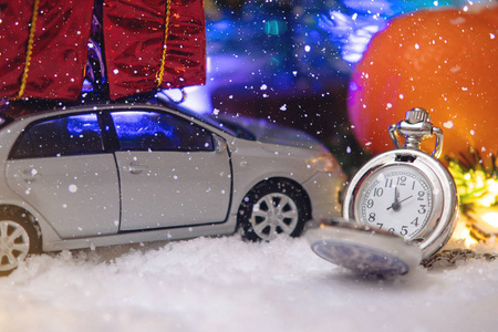 假日前夕带着一辆车和礼物在雪地里的怀表。 等待圣诞节和新年魔力的概念