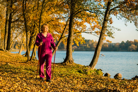 芬兰的运动北欧步行。老年妇女在森林或公园徒步旅行。积极健康的生活方式..