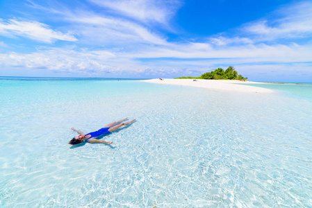 女子日光浴在风景秀丽的白沙滩上,后景,晴天,绿松石透明水,真人.