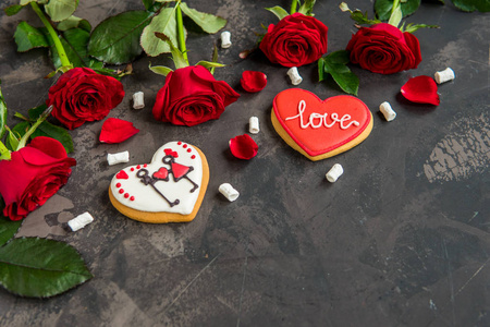 红色玫瑰和饼干形状的心与文字爱，黑暗的背景复制空间。
