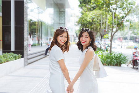朋友们去购物。两个年轻的女人拿着袋子在购物中心散步