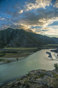 阿尔泰自然的美丽景色和景观。 傍晚的山河在日落的背景下，群山和蓝天的背景下，傍晚有云。