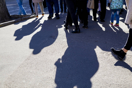 阳光影子许多人的腿在拥挤的街道上行走,阳光明媚的日子里人们的影子