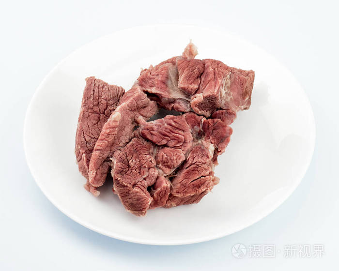 白色背景特写的白色盘子上的一块煮牛肉