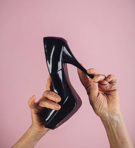 老太婆手里拿着黑色高跟鞋穿晚礼服.时尚为老年人成熟.