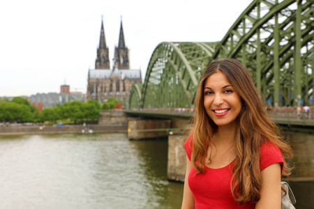 欧洲游客女。 快乐的微笑女孩在德国旅行。 美丽的旅行者女孩在镜头前摆姿势，在莱茵河上有古龙水大教堂和霍恩佐伦桥。
