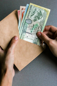 手拿着尼泊尔货币的信封。