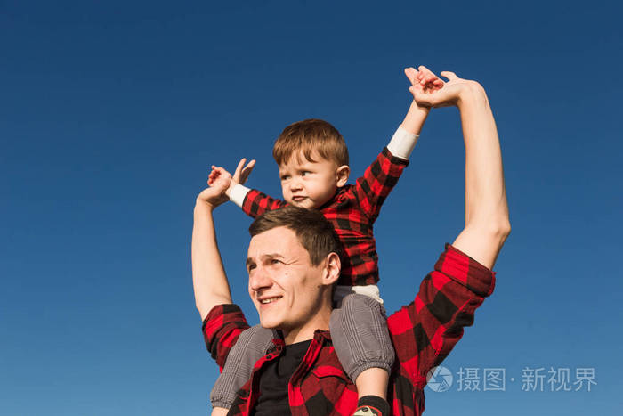 年轻快乐的家庭与孩子们在大自然中的乐趣.坐在父亲肩膀上的小男孩
