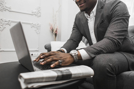 年轻的非洲裔美国商人穿着灰色西装在笔记本电脑后面工作