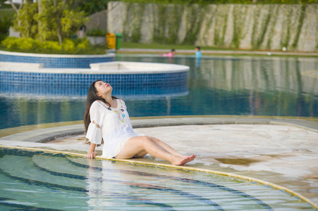 户外生活方式肖像，年轻，快乐，美丽的亚洲旅游妇女，在热带度假游泳池放松，享受暑假，微笑，愉快，放松。