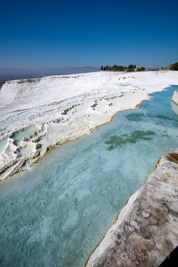 白色梯田与绿松石热水池在日出的阳光帕穆卡勒土耳其旅游地标。 广角垂直图像。