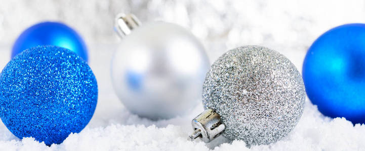新年横幅与蓝色，银色和白色圣诞球在雪地上抽象的冬季背景。 圣诞装饰。 圣诞快乐。