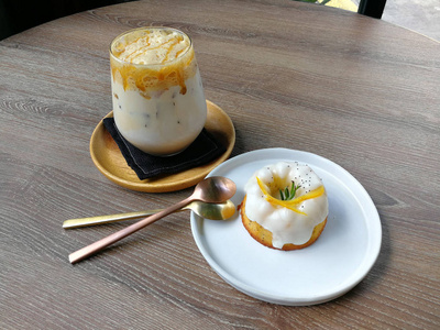 木桌上的冰焦糖咖啡和橙色酸奶蛋糕