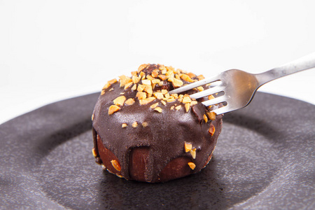 朗姆酒球，用巧克力和坚果装饰在黑色盘子上，白色背景上用叉子吃