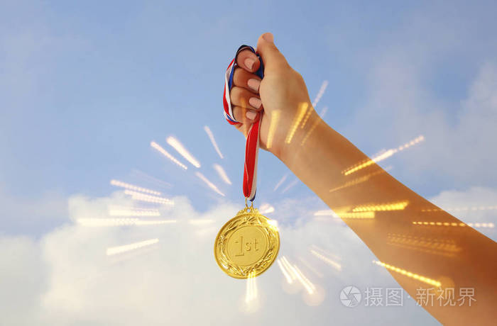 女人举起手拿着金牌对抗天空 奖励和胜利概念